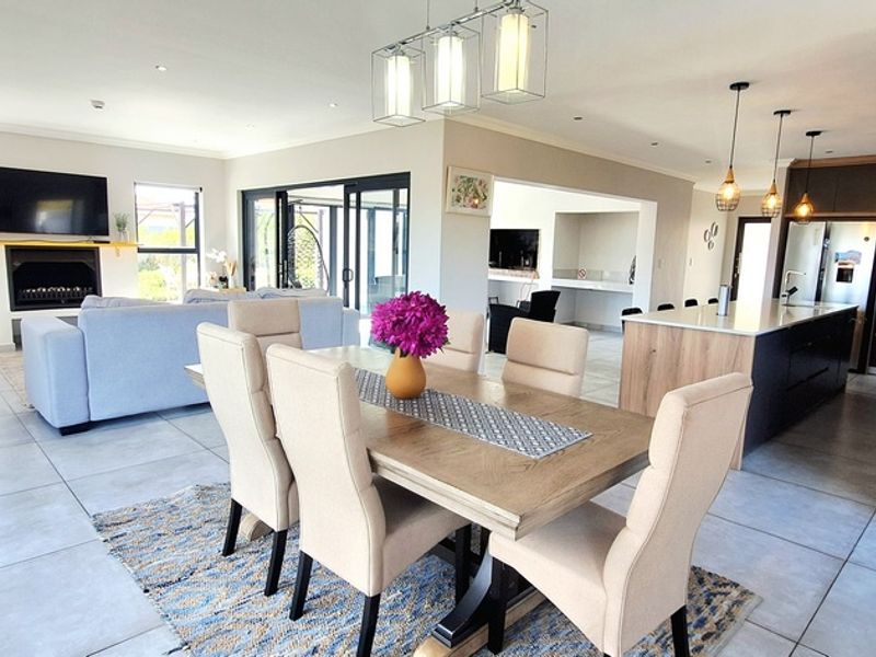 Spacious open-plan living, dining, and kitchen area featuring modern cabinetry, a central island, fireplace, and large sliding doors leading to the outdoors.