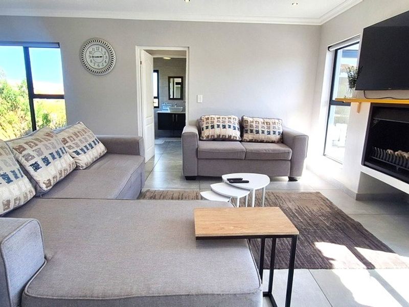A bright and modern living room featuring a built-in fireplace, large windows with natural light, and neutral tiled flooring.