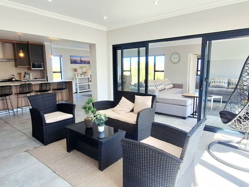 Spacious open-plan living area featuring a modern kitchen with island, sleek cabinetry, and large sliding doors leading to an outdoor space.