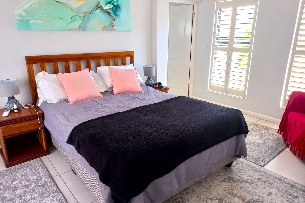 A well-maintained bedroom featuring tiled flooring and white plantation shutters, providing a bright and comfortable living space.