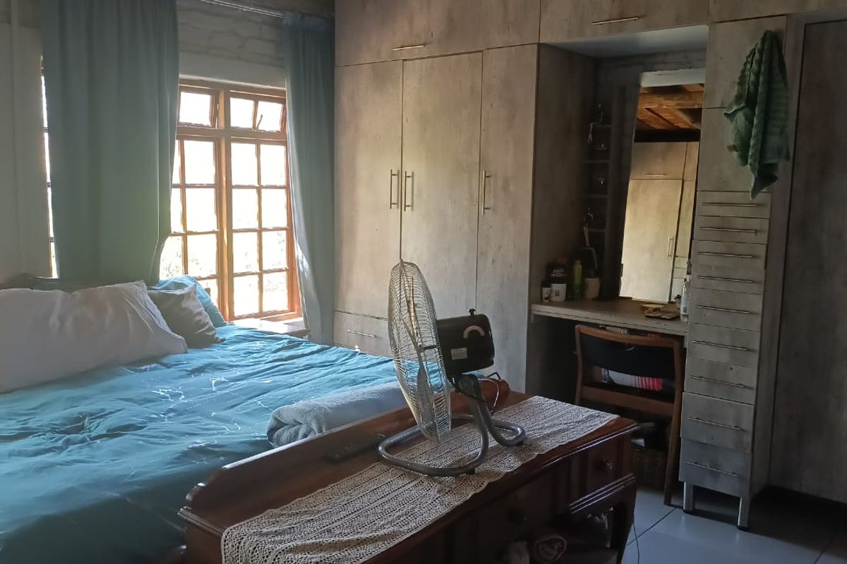 A bedroom featuring built-in cupboards with a integrated vanity area and timber-framed windows allowing natural light.