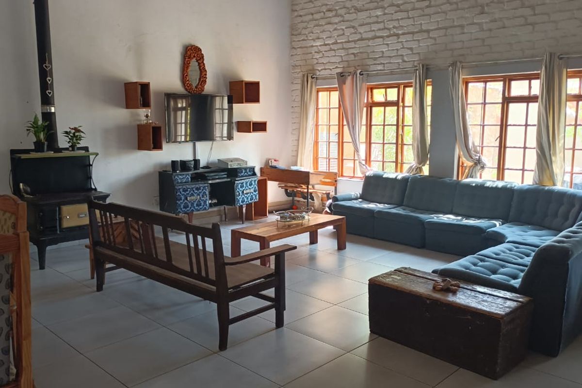 Spacious living room featuring a wood-burning stove, exposed brick feature wall, and large timber-framed windows providing ample natural light.