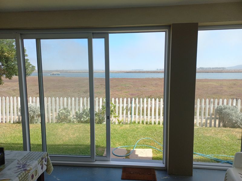 Covered patio area featuring large sliding glass doors with direct views of the garden and lagoon.