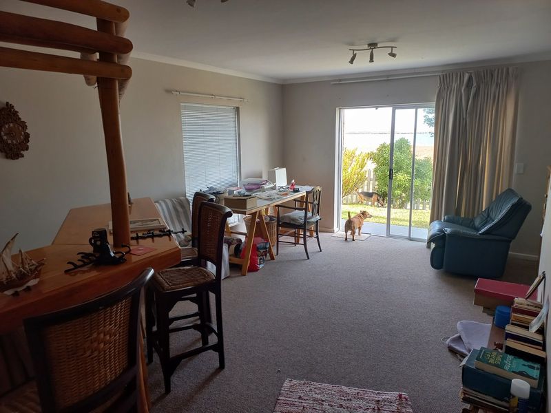 A living room featuring carpet flooring, a breakfast bar, and a sliding glass door providing access to the rear garden.