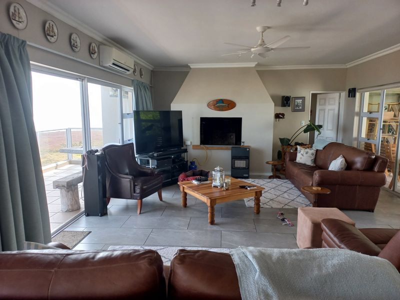 Spacious living room featuring tiled floors, a built-in fireplace, ceiling fan, and large sliding glass doors providing access to an outdoor patio area.