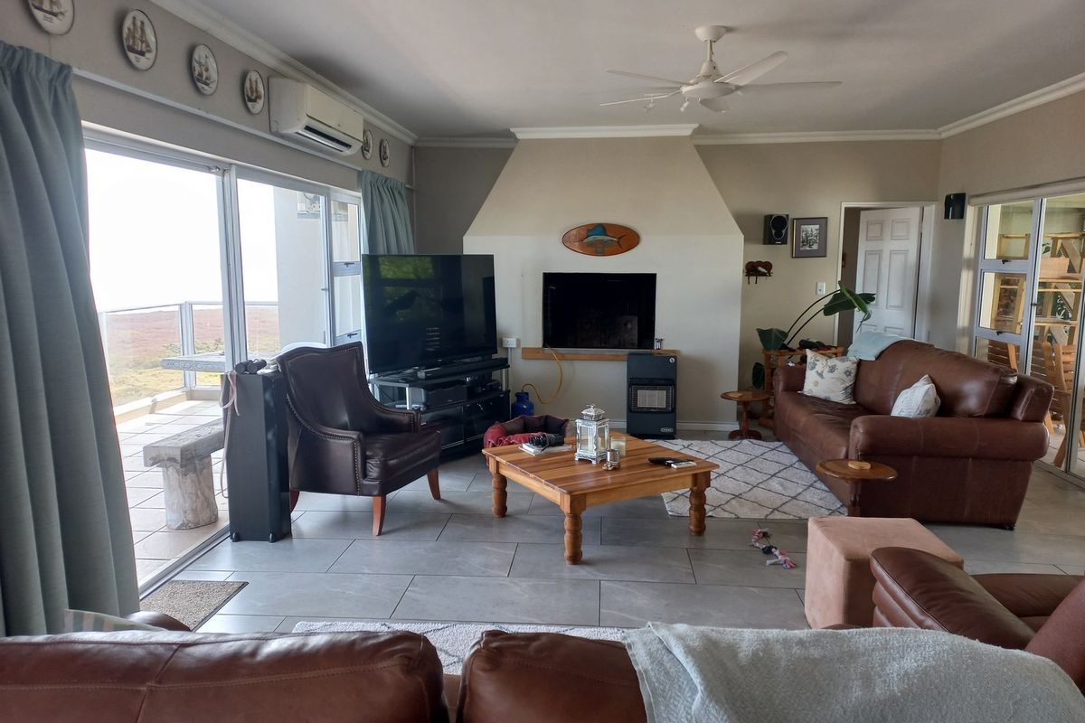 Spacious living room featuring tiled floors, a built-in fireplace, ceiling fan, and large sliding glass doors providing access to an outdoor patio area.