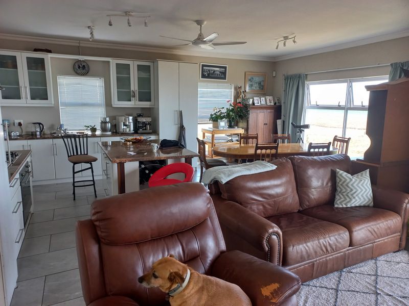 Spacious open-plan living and kitchen area featuring tiled floors, a central island, and large sliding doors providing natural light and outdoor access.