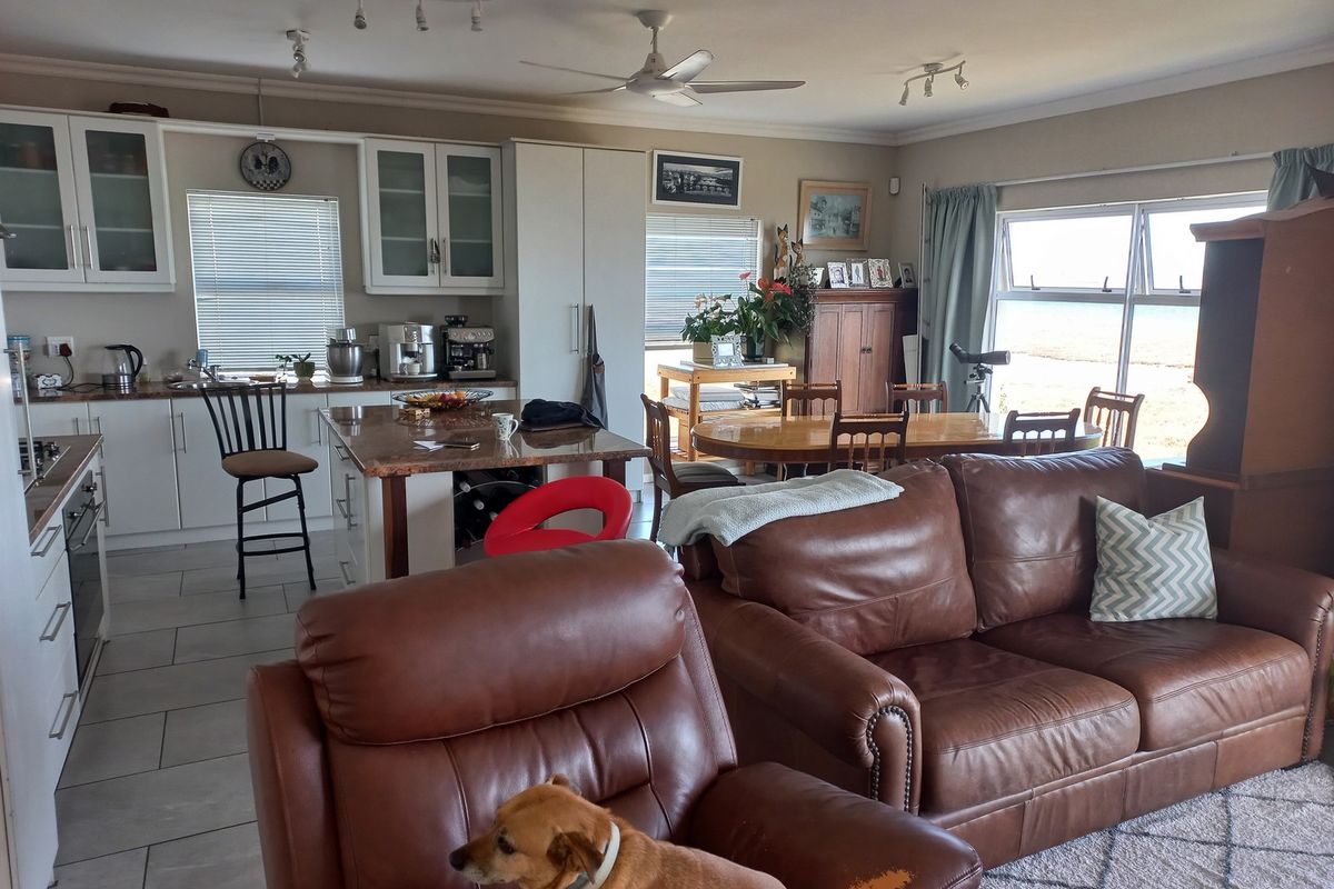 Spacious open-plan living and kitchen area featuring tiled floors, a central island, and large sliding doors providing natural light and outdoor access.