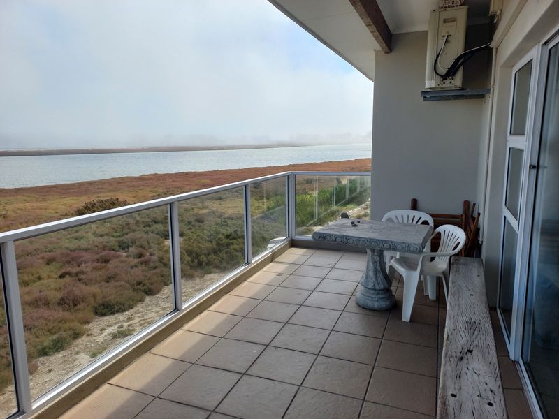 Covered balcony featuring tiled flooring, a glass balustrade, and direct views over the water and natural landscape.