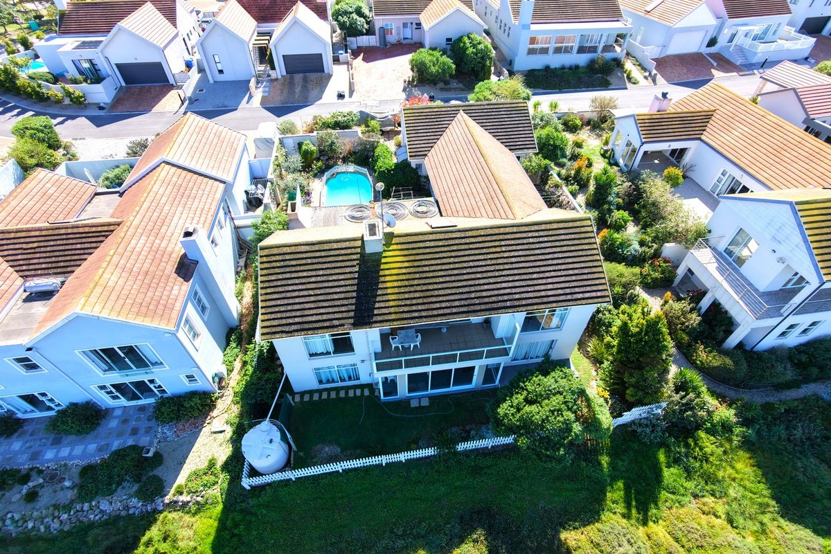 Aerial view of a residential property featuring a tiled roof, private swimming pool, balcony, and landscaped garden area within a suburban estate.