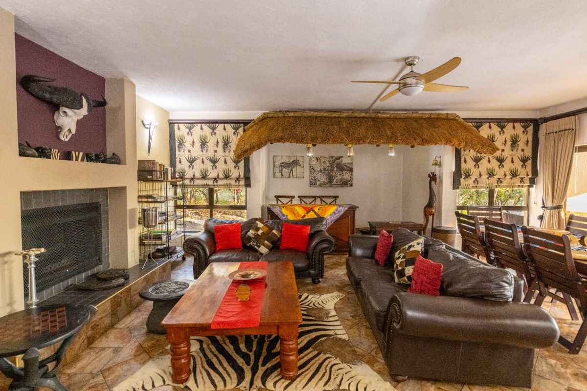 Spacious living room featuring a built-in fireplace, tiled flooring, and a unique thatched architectural feature, creating a distinct rustic atmosphere.