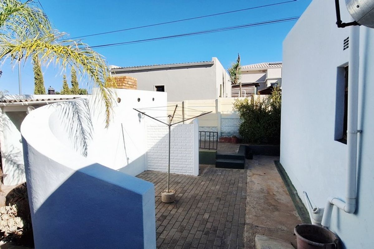 A private rear courtyard featuring paved flooring, a curved feature wall, and a built-in outdoor structure, providing a functional outdoor space.