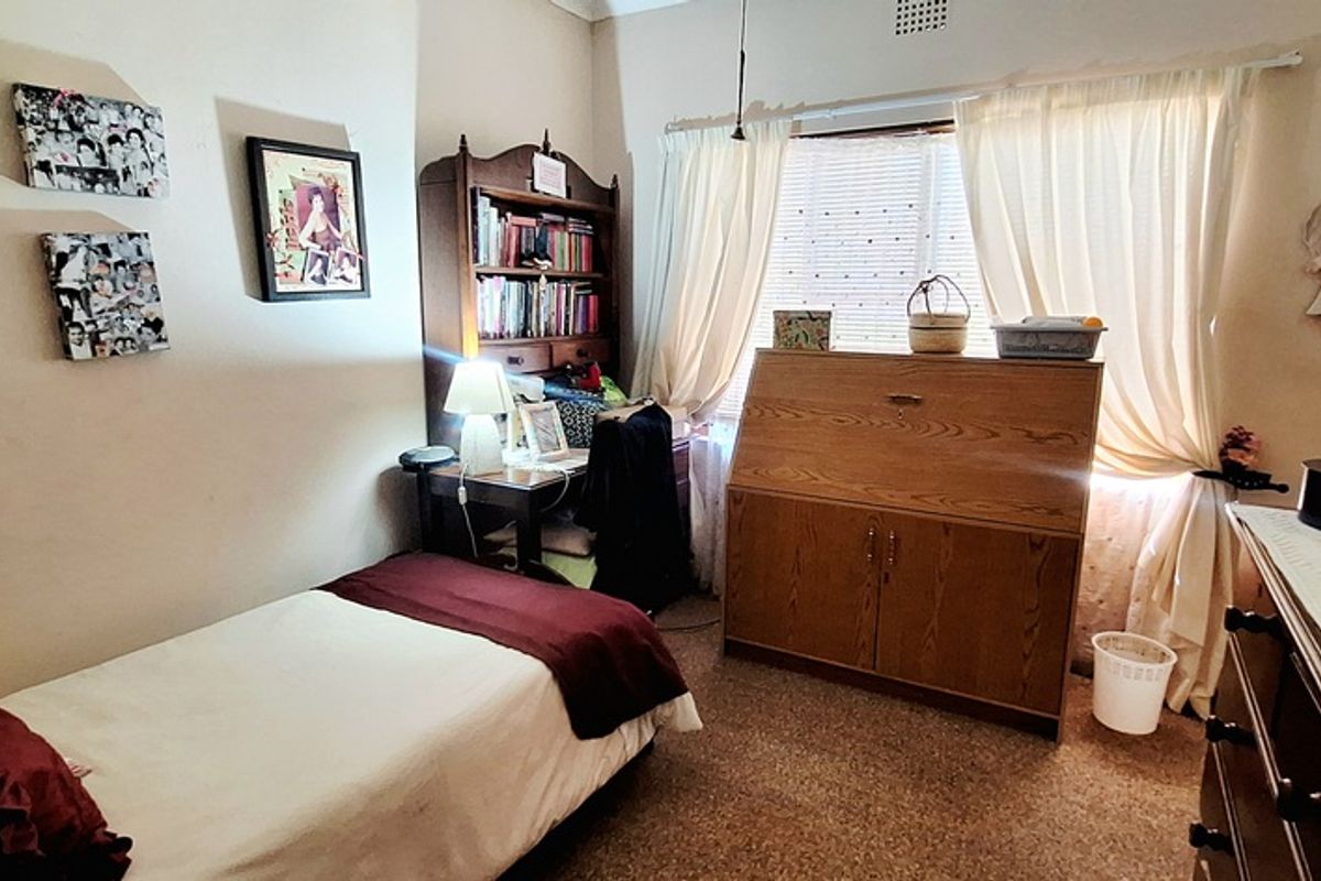 A functional bedroom featuring built-in cupboards and a window with natural light, providing a comfortable and practical living space.