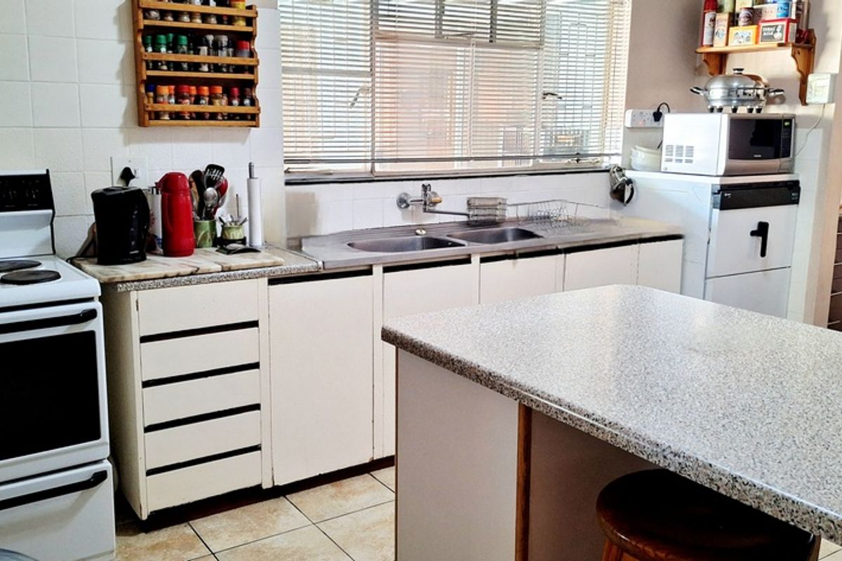 Functional kitchen featuring white cabinetry, a freestanding stove, double basin sink, and a breakfast nook counter with tiled flooring.