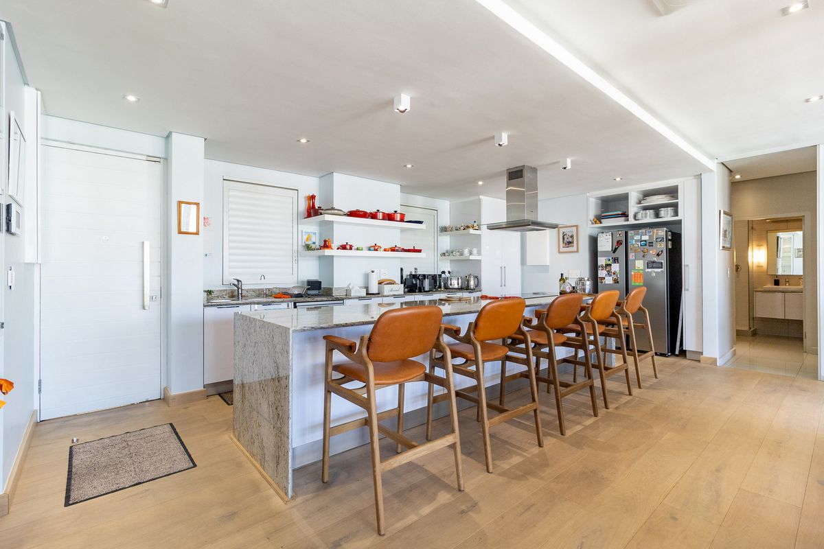Modern open-plan kitchen featuring a large granite island, sleek cabinetry, stainless steel extractor fan, and light wood flooring, creating a bright and functional space.