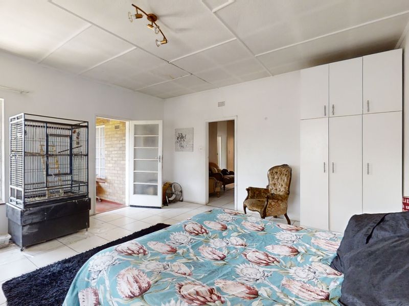 Spacious bedroom featuring built-in cupboards, tiled flooring, and direct access to an adjoining patio area.