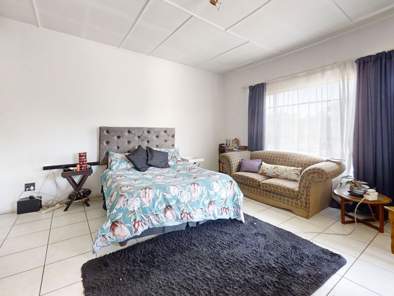 Spacious bedroom featuring built-in cupboards, tiled flooring, and a large window allowing for natural light.