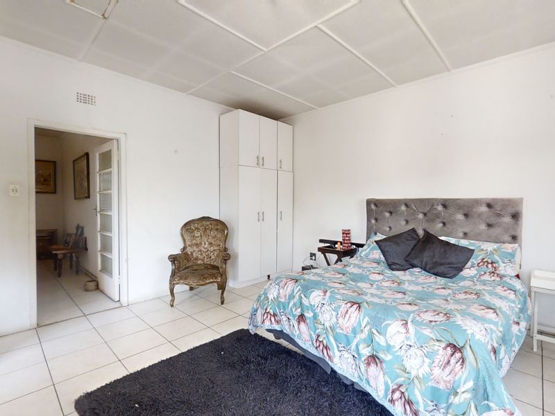 A bedroom featuring tiled flooring, a built-in wardrobe, and a panel ceiling, offering a functional space ready for cosmetic updates.
