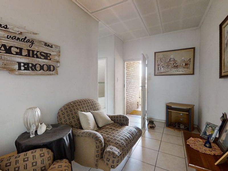 A living room area featuring tiled flooring and a drop ceiling, providing a functional space with direct access to an exterior entrance.