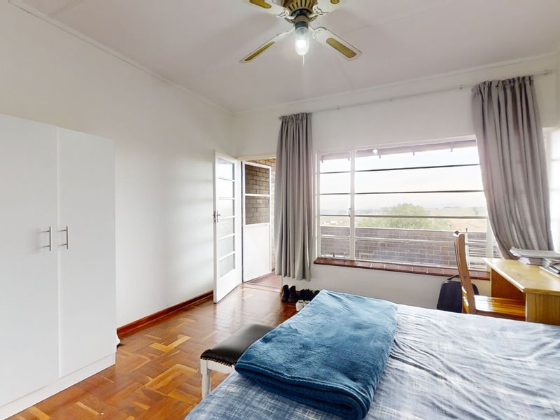 A bedroom featuring parquet flooring, a ceiling fan, a built-in wardrobe, and direct access to an outdoor balcony area.