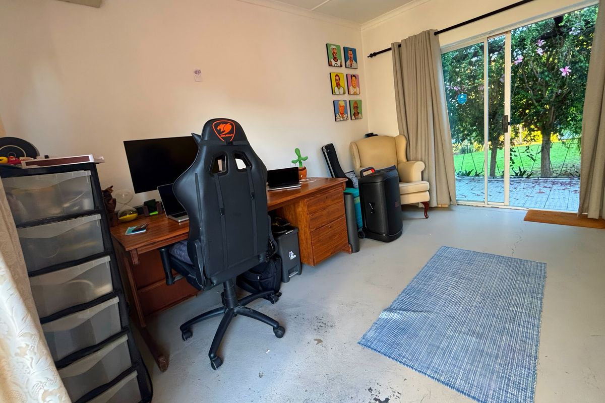 A multi-purpose room featuring a wall-mounted air conditioning unit and sliding glass doors providing direct access to the rear garden.
