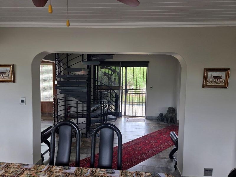 Living area featuring a distinctive spiral staircase, tiled flooring, and an arched entryway leading to a secure exterior door.