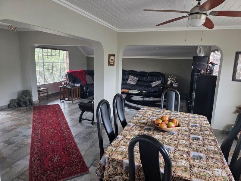 An open-plan living and dining area featuring tiled flooring, a tongue and groove ceiling with a fan, and architectural archways connecting the spaces.