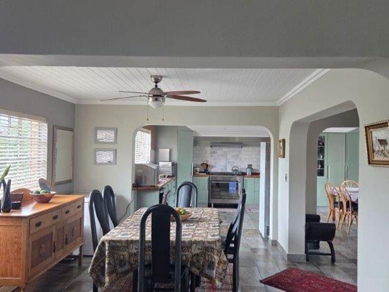 Open plan dining area featuring tiled floors and an archway leading to a functional kitchen with built-in cabinetry and a freestanding oven.