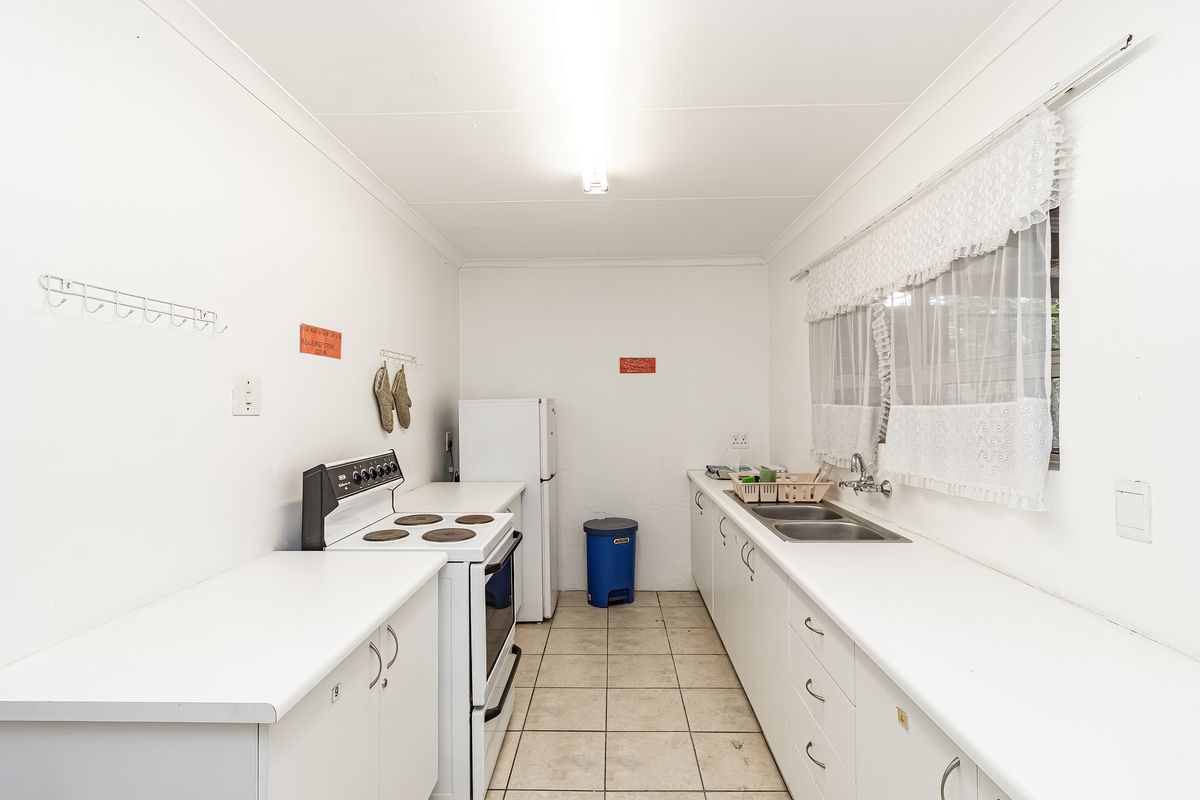 A functional galley-style kitchen featuring white cabinetry, a double basin sink, and a freestanding electric stove.