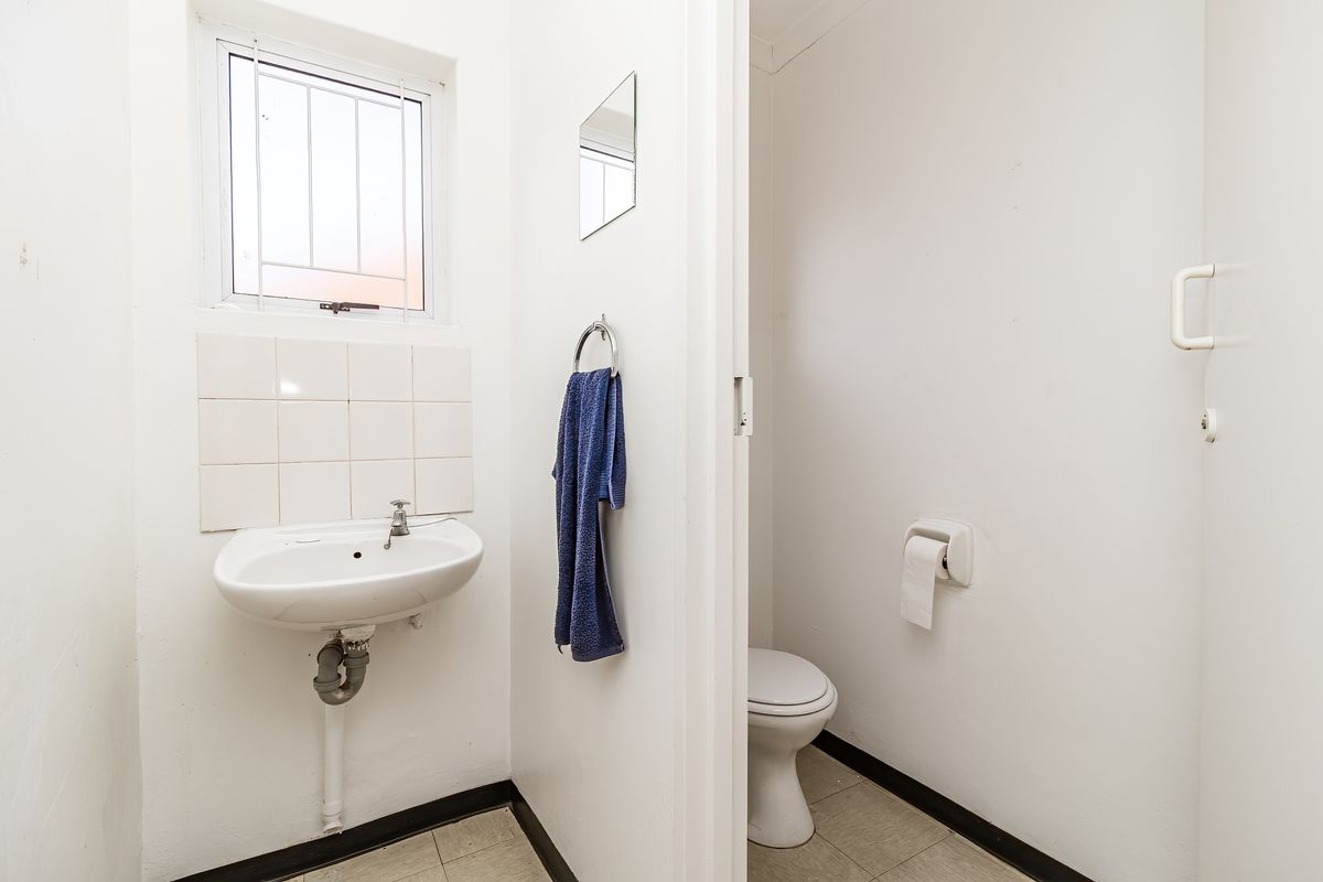 A compact guest cloakroom featuring a wall-mounted basin with tiled splashback and a separate toilet area.