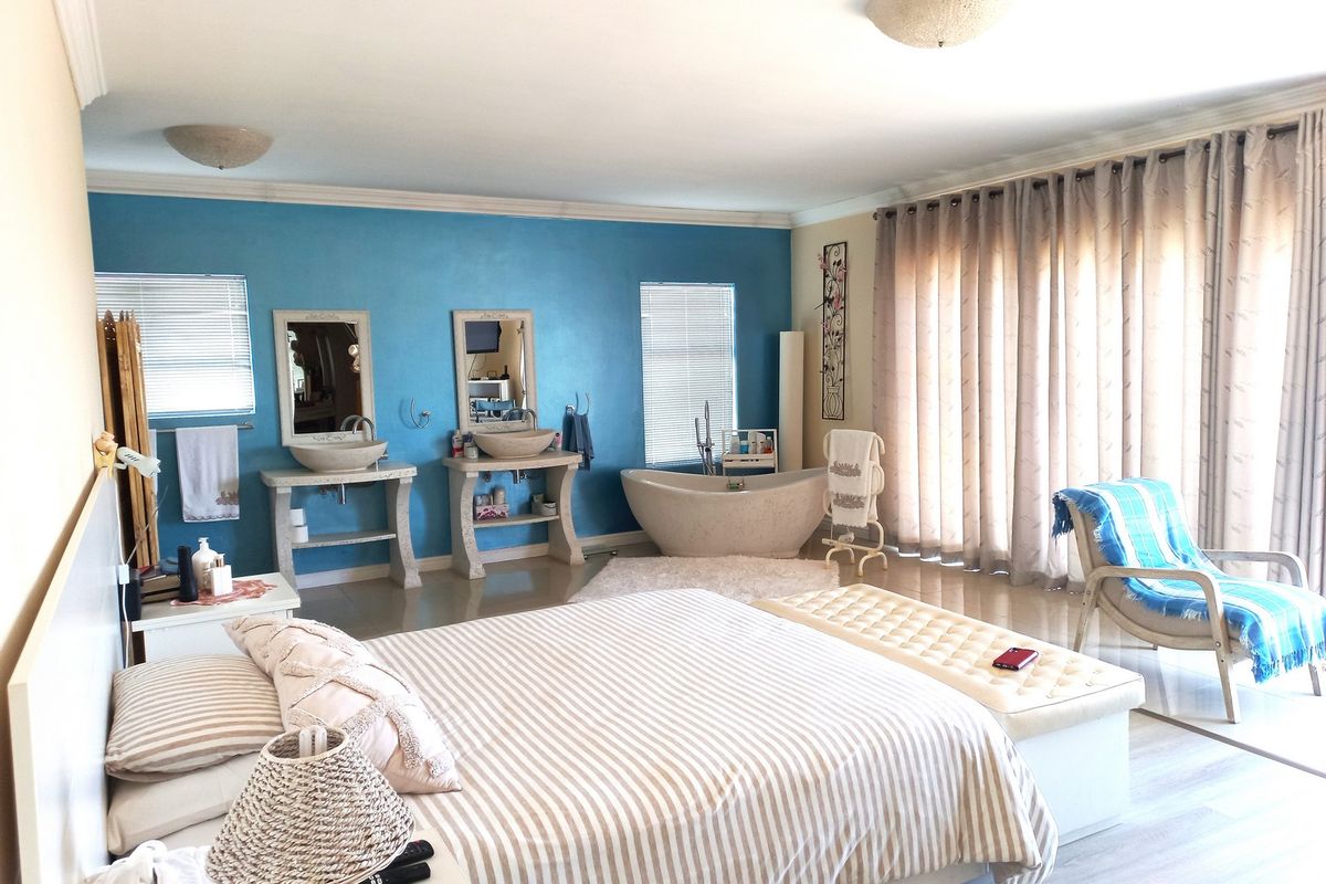 Spacious bedroom featuring an integrated ensuite area with a freestanding bathtub and dual vessel sink vanity consoles.