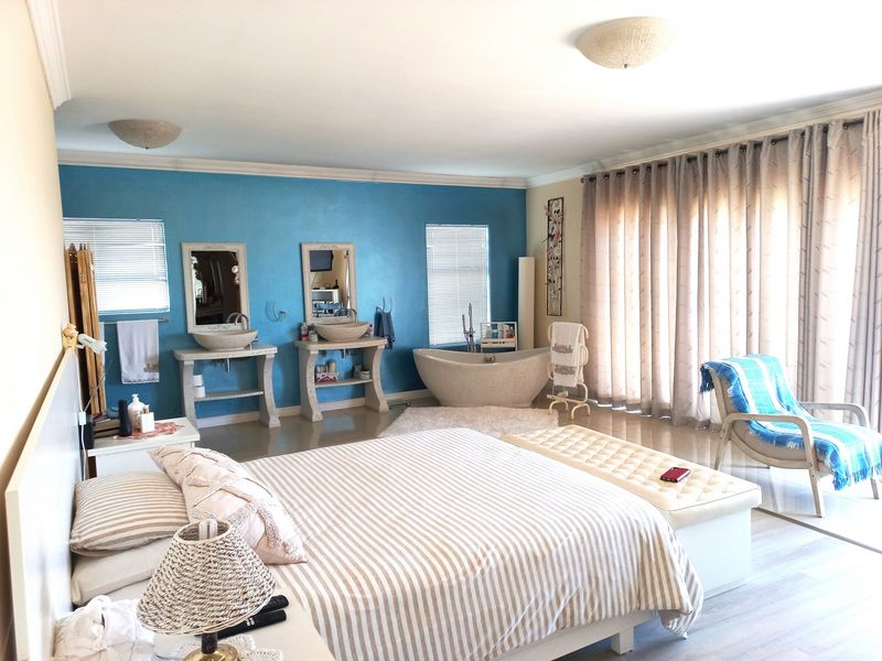 Spacious bedroom featuring an integrated ensuite area with a freestanding bathtub and dual vessel sink vanity consoles.