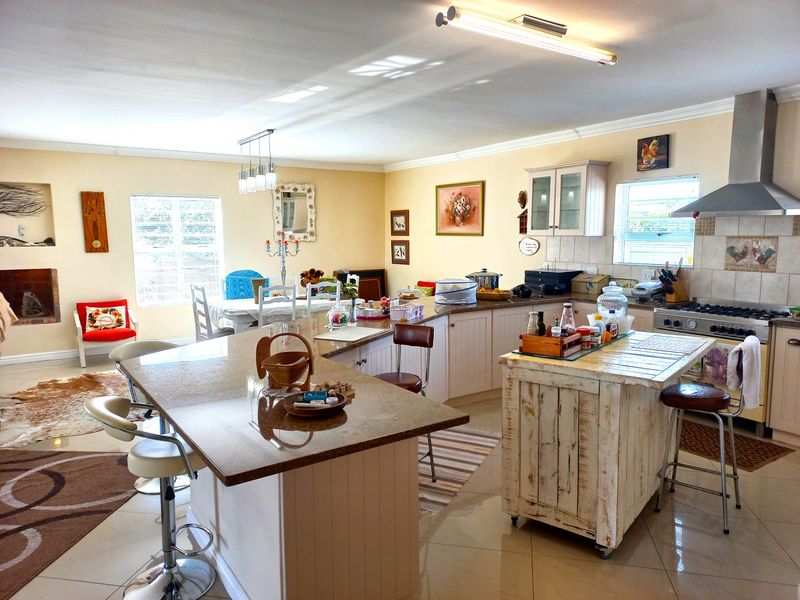 Spacious open-plan kitchen and living area featuring a large granite island, gas stove, stainless steel extractor, and a cozy recessed fireplace.