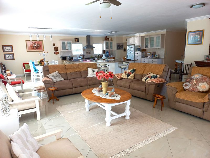 Spacious open-plan living area featuring a kitchen with granite countertops, central island, and tiled flooring, seamlessly flowing into the lounge space.