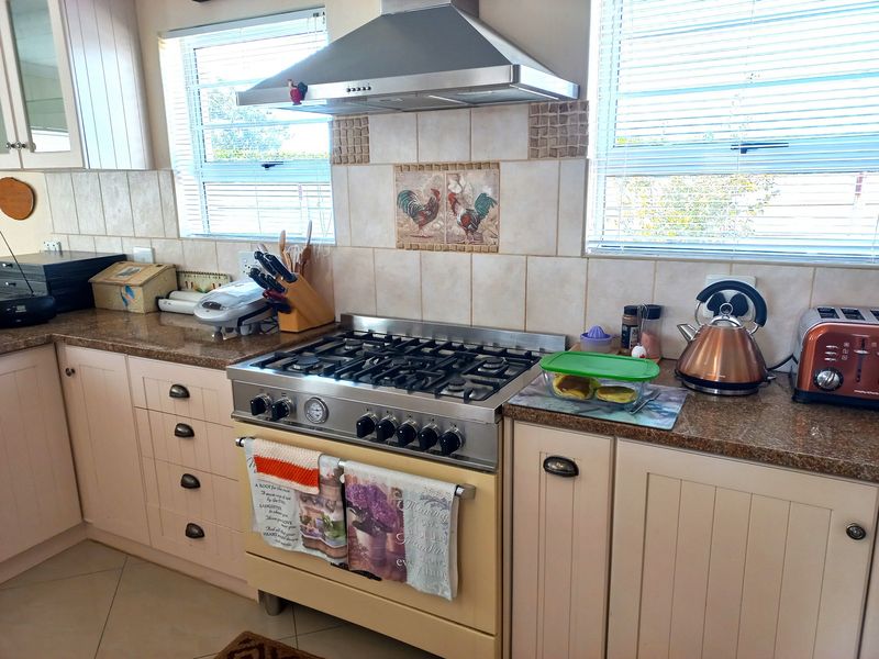 A functional kitchen featuring a gas stove, stainless steel extractor fan, granite countertops, and tiled backsplash with neutral cabinetry.
