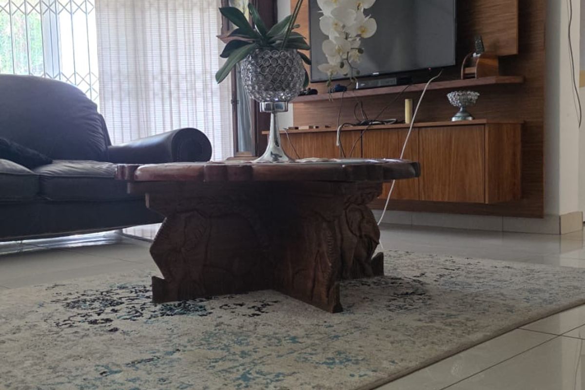 A living room featuring tiled flooring, crown molding, and a built-in wooden media console with a wall-mounted air conditioning unit.