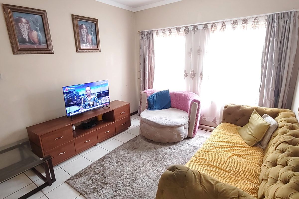 A comfortable living room featuring tiled flooring and large windows that allow for ample natural light.