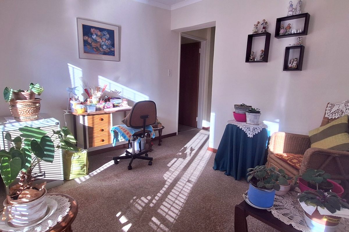 A sunlit bedroom featuring carpeted flooring and a doorway leading to an adjacent hallway.