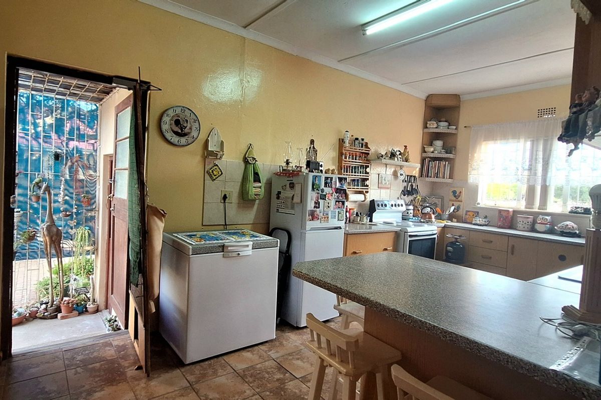 A functional kitchen featuring laminate countertops, built-in cabinetry, and direct access to an outdoor area, offering potential for modernization and layout updates.