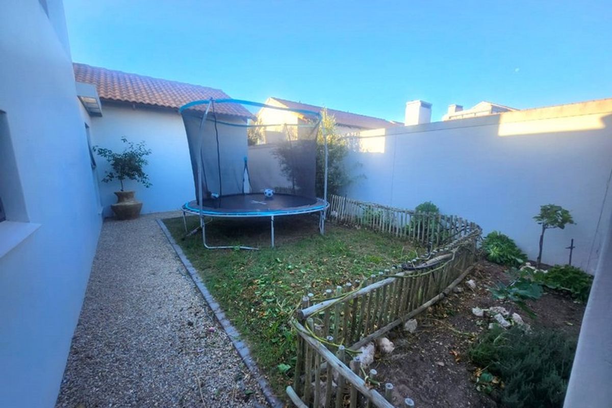 A private rear garden area featuring a gravel pathway, a small lawn section, and perimeter boundary walls.