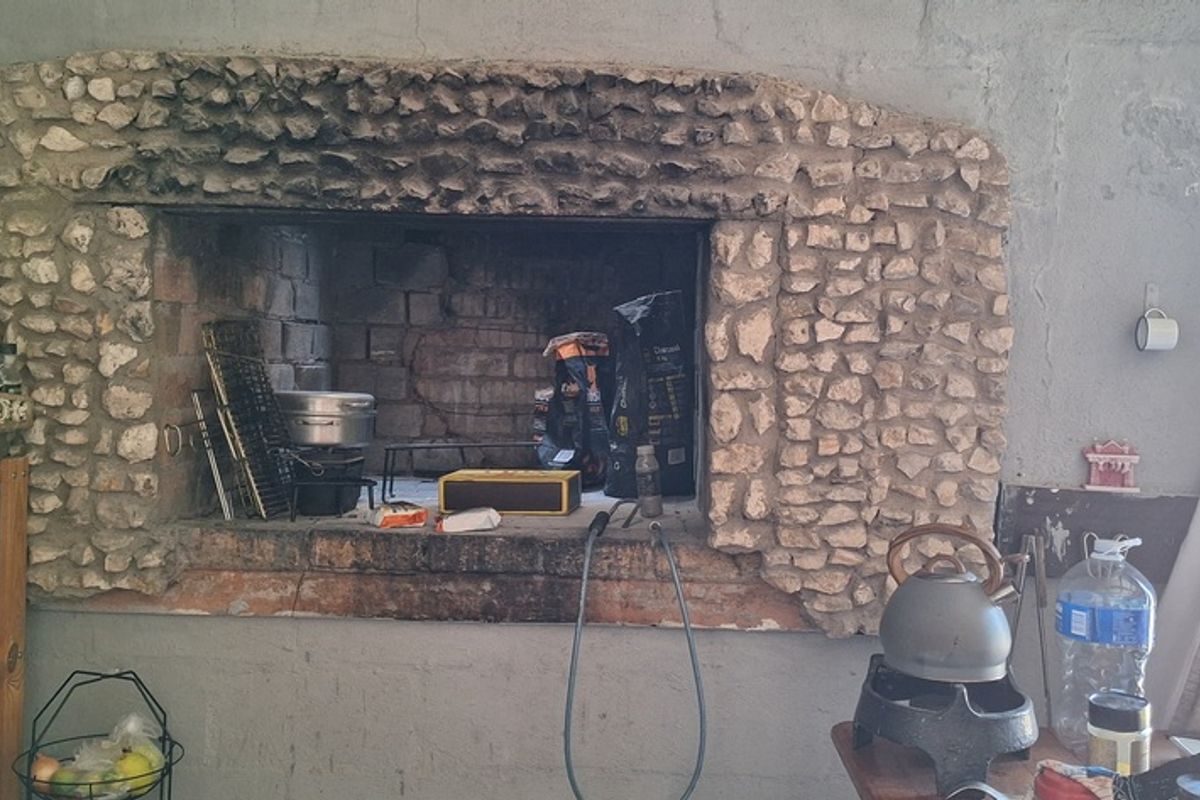 Indoor built-in stone fireplace with brick interior, showing signs of heavy use and wear in a rustic living space.