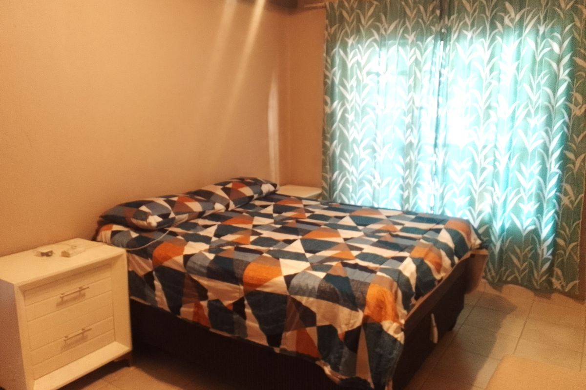 A bedroom featuring tiled flooring and a window with curtains, providing a functional and comfortable living space.