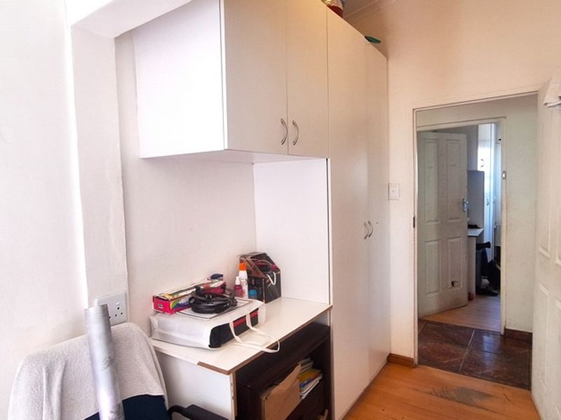 A functional hallway featuring built-in storage cupboards, wooden flooring, and access to adjacent rooms through internal doors.