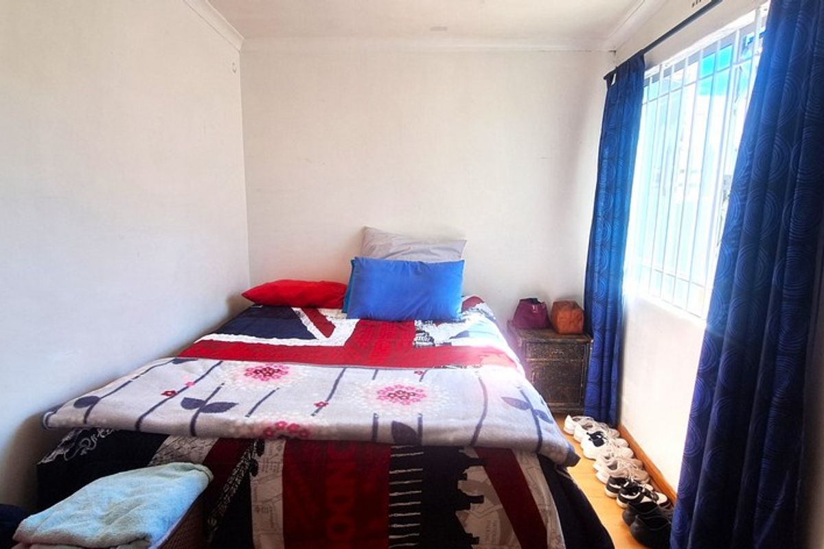 A compact bedroom featuring security bars on the window and simple coving, providing a functional space for rest.