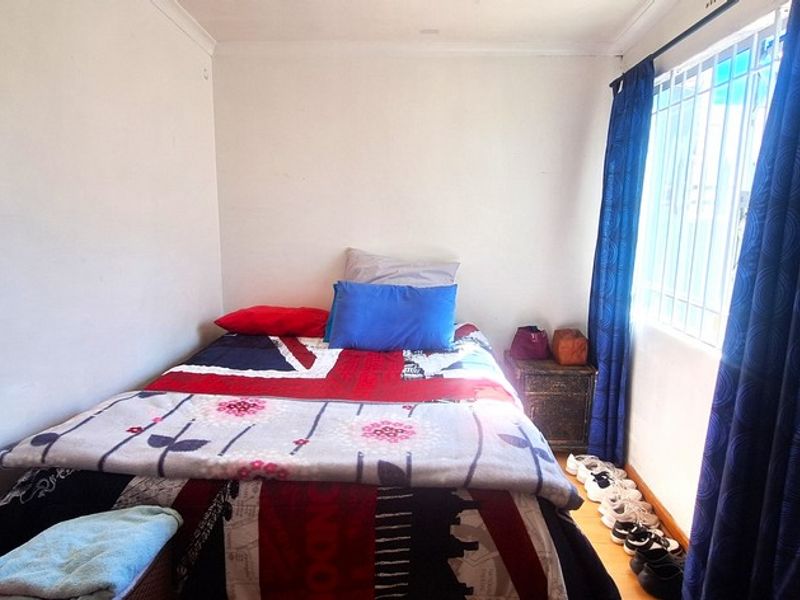 A compact bedroom featuring security bars on the window and simple coving, providing a functional space for rest.