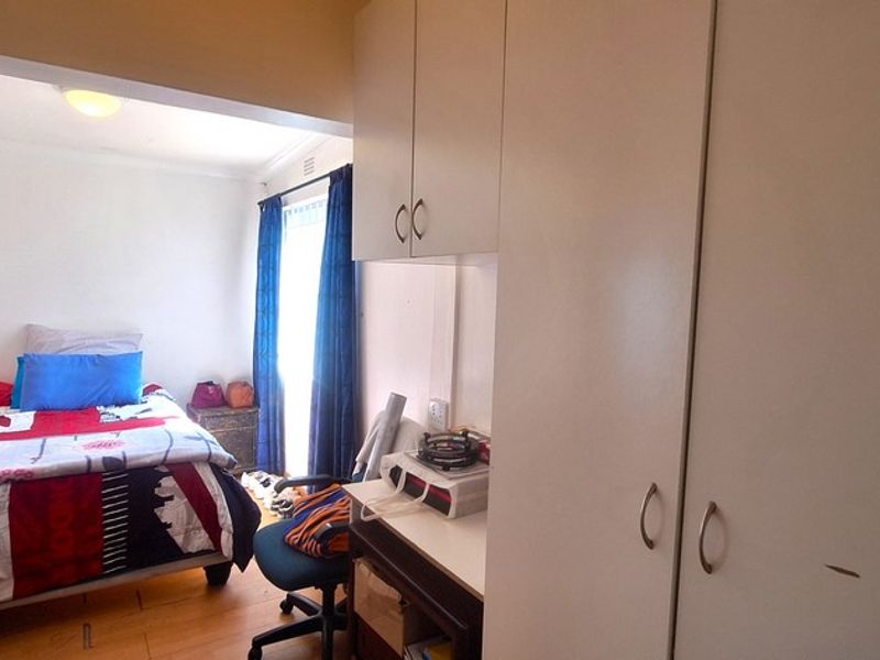 A bedroom featuring wooden flooring and built-in cupboards, providing functional storage space within the room.
