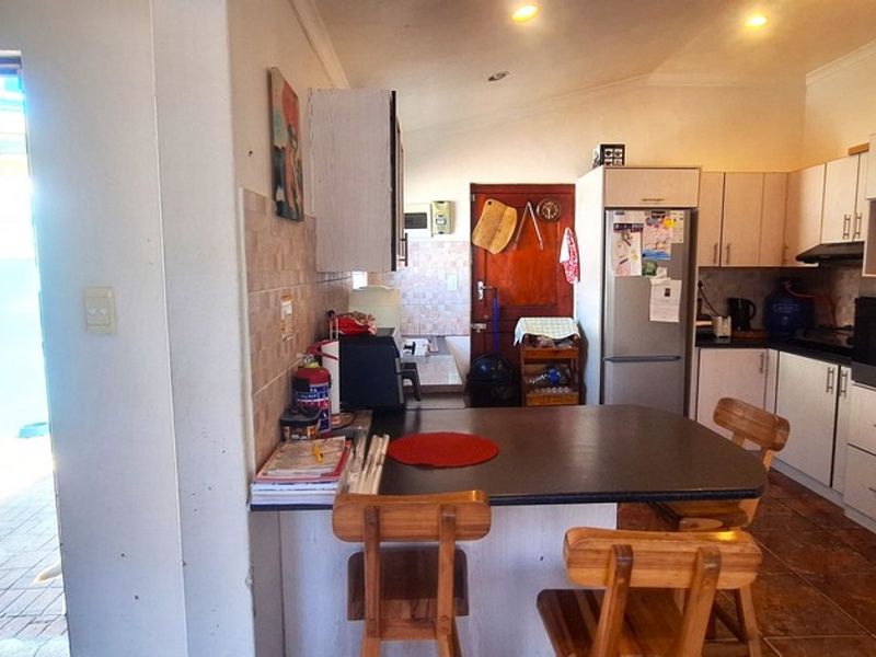 Functional kitchen featuring built-in cabinetry, integrated oven, extractor fan, and a breakfast bar, with direct access to an outdoor patio area.