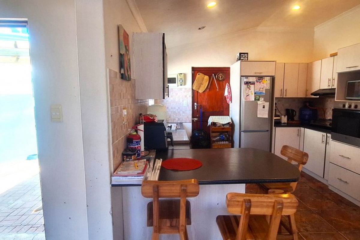 Functional kitchen featuring built-in cabinetry, integrated oven, extractor fan, and a breakfast bar, with direct access to an outdoor patio area.