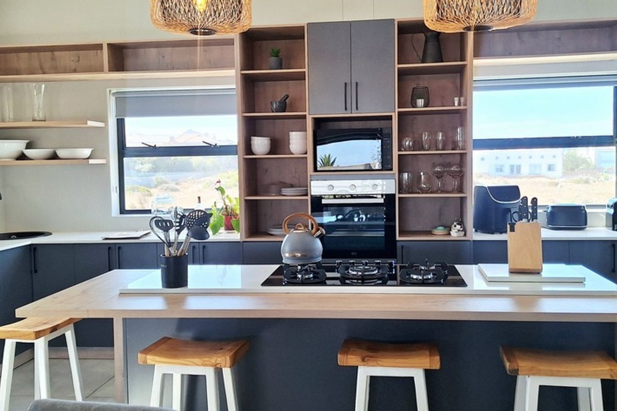 Modern kitchen featuring a central island with a built-in gas hob, sleek cabinetry, open shelving, and integrated oven and microwave.