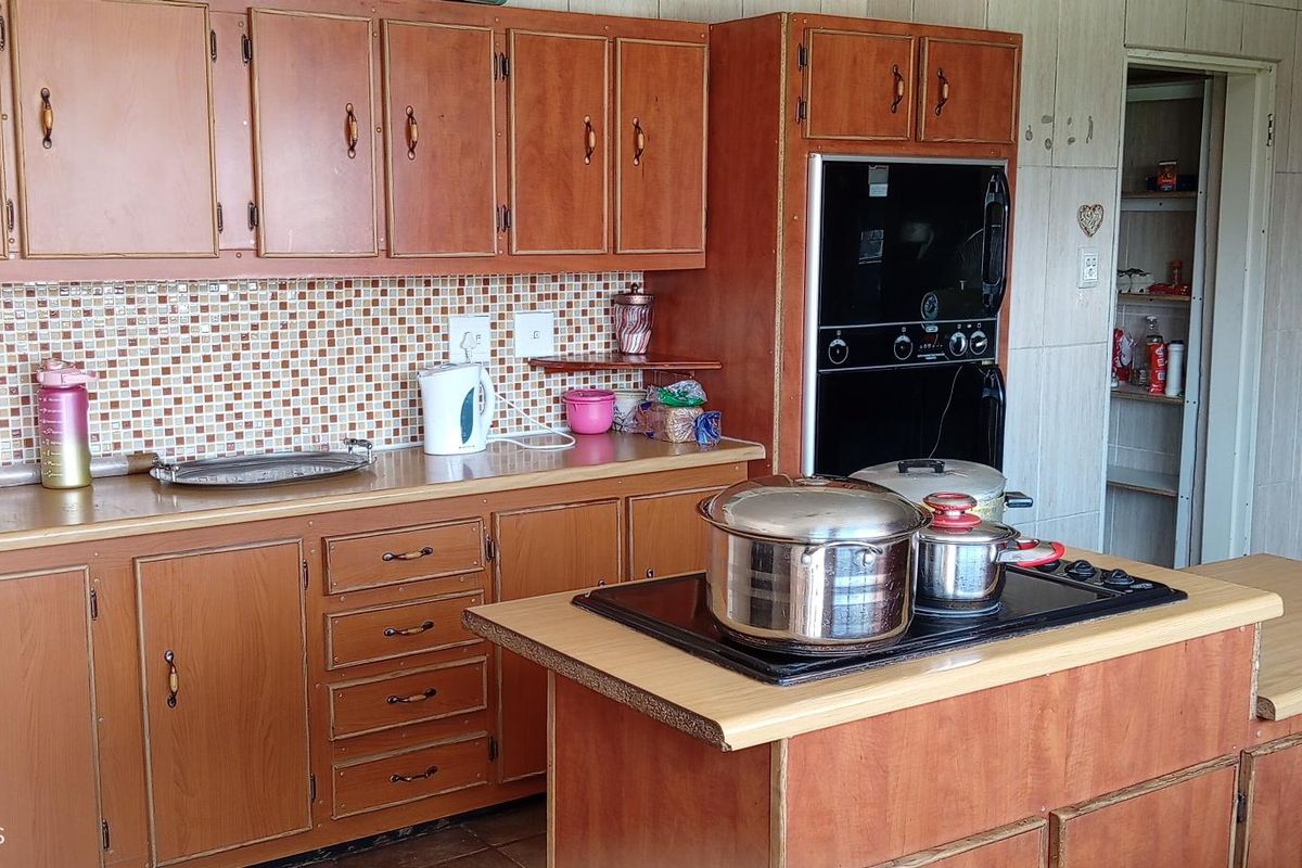 A functional kitchen featuring wood-finish cabinetry, a built-in oven, a central island with a cooktop, and a tiled backsplash.